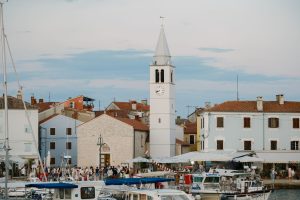 Picturesque Croatian harbor with clock tower and boats at dusk.