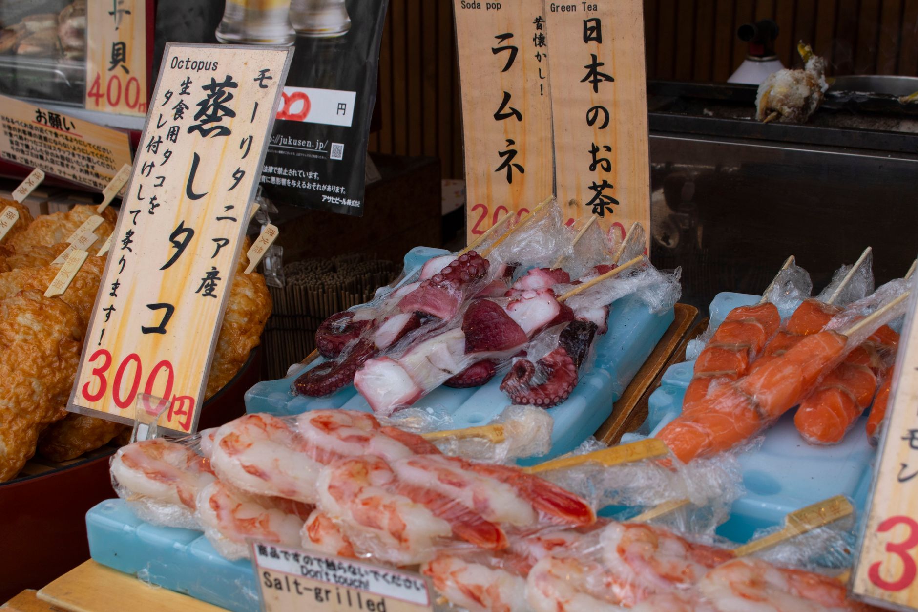 Colorful seafood skewer display at a local Japanese market with visible price tags.