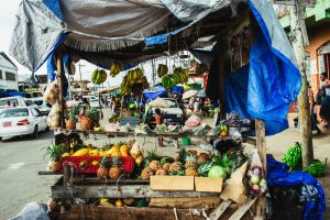 Fresh fruits displayed at a colorful roadside market stall on a busy street.
