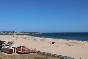 A stunning beach view of Portimão, Portugal, featuring golden sand and the blue ocean under a clear sky.