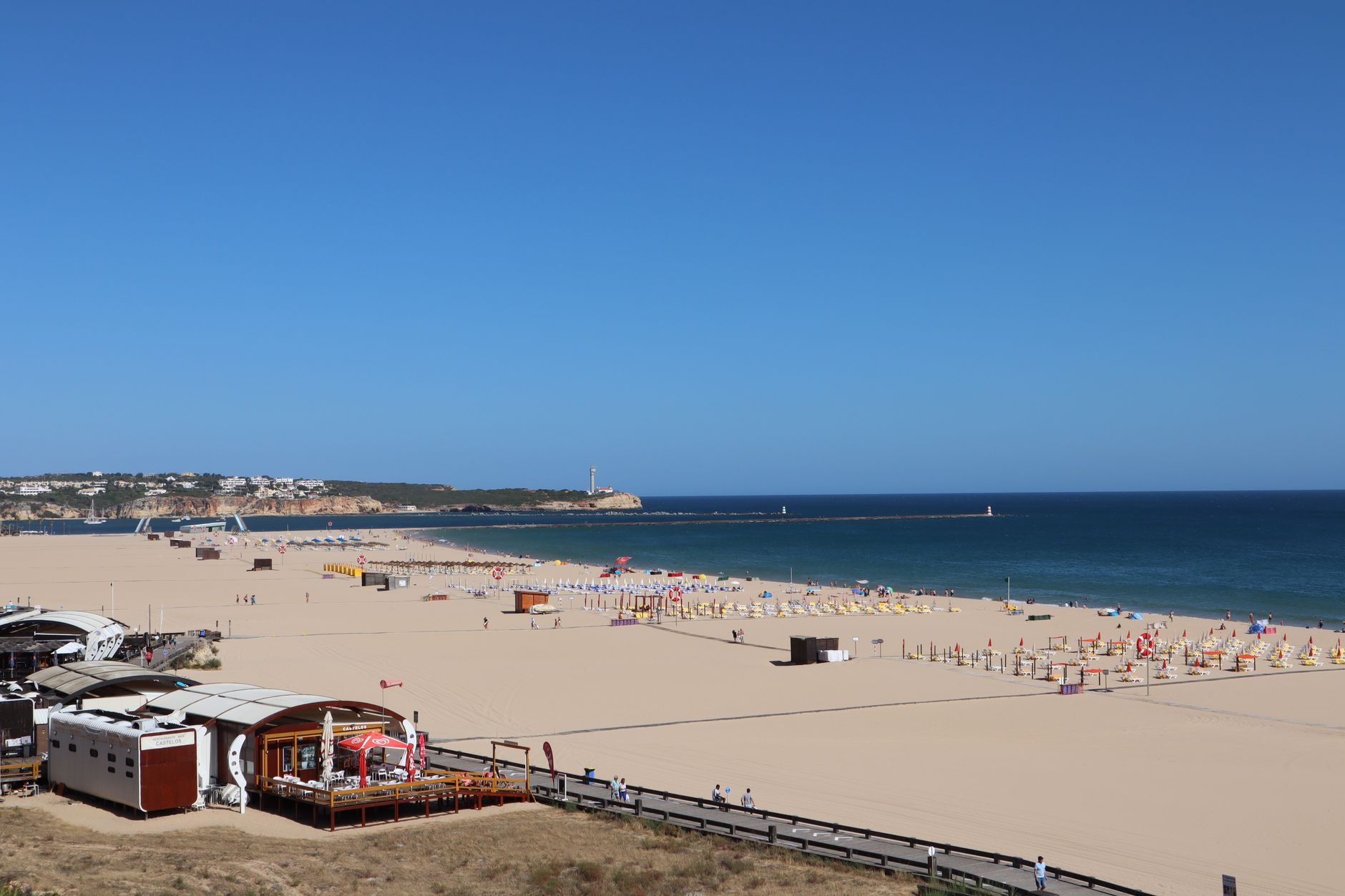 A stunning beach view of Portimão, Portugal, featuring golden sand and the blue ocean under a clear sky.