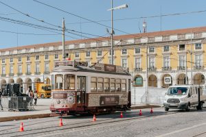 A classic tram on Lisbon's city street beside historic yellow architecture.