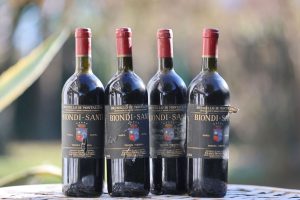 A set of Brunello di Montalcino Biondi-Santi wine bottles arranged on an outdoor table.