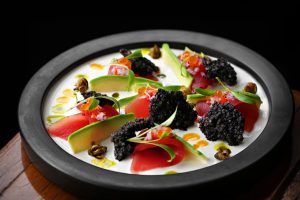 Delicious gourmet ceviche plate with fresh avocado, caviar, and vibrant garnishes.